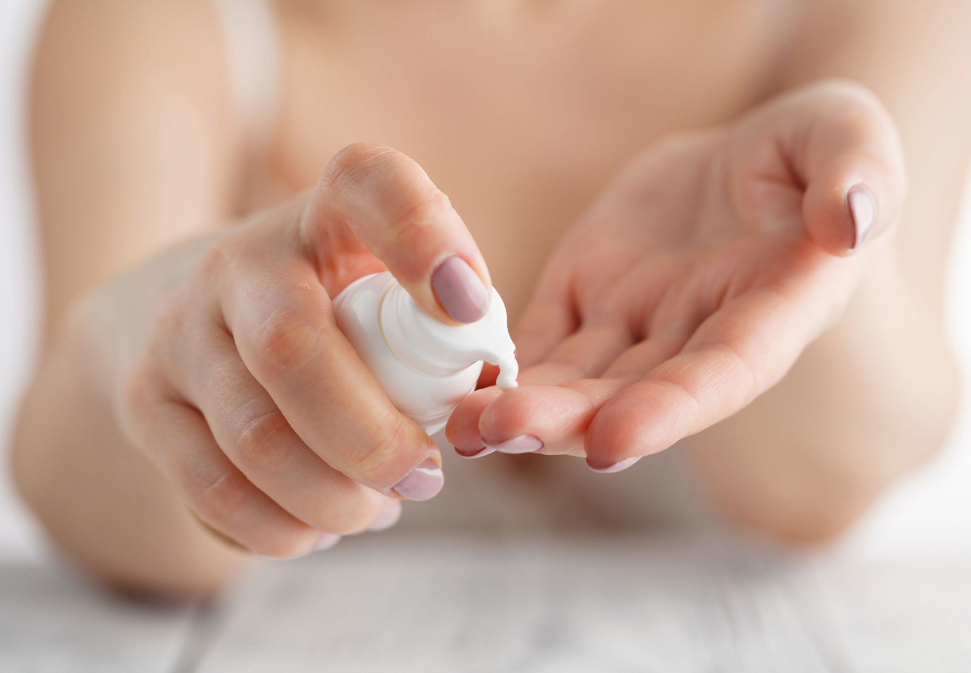 Aptar Pharma's white plastic Airless+ system is used to precisely dispense white cream onto a woman's hands.