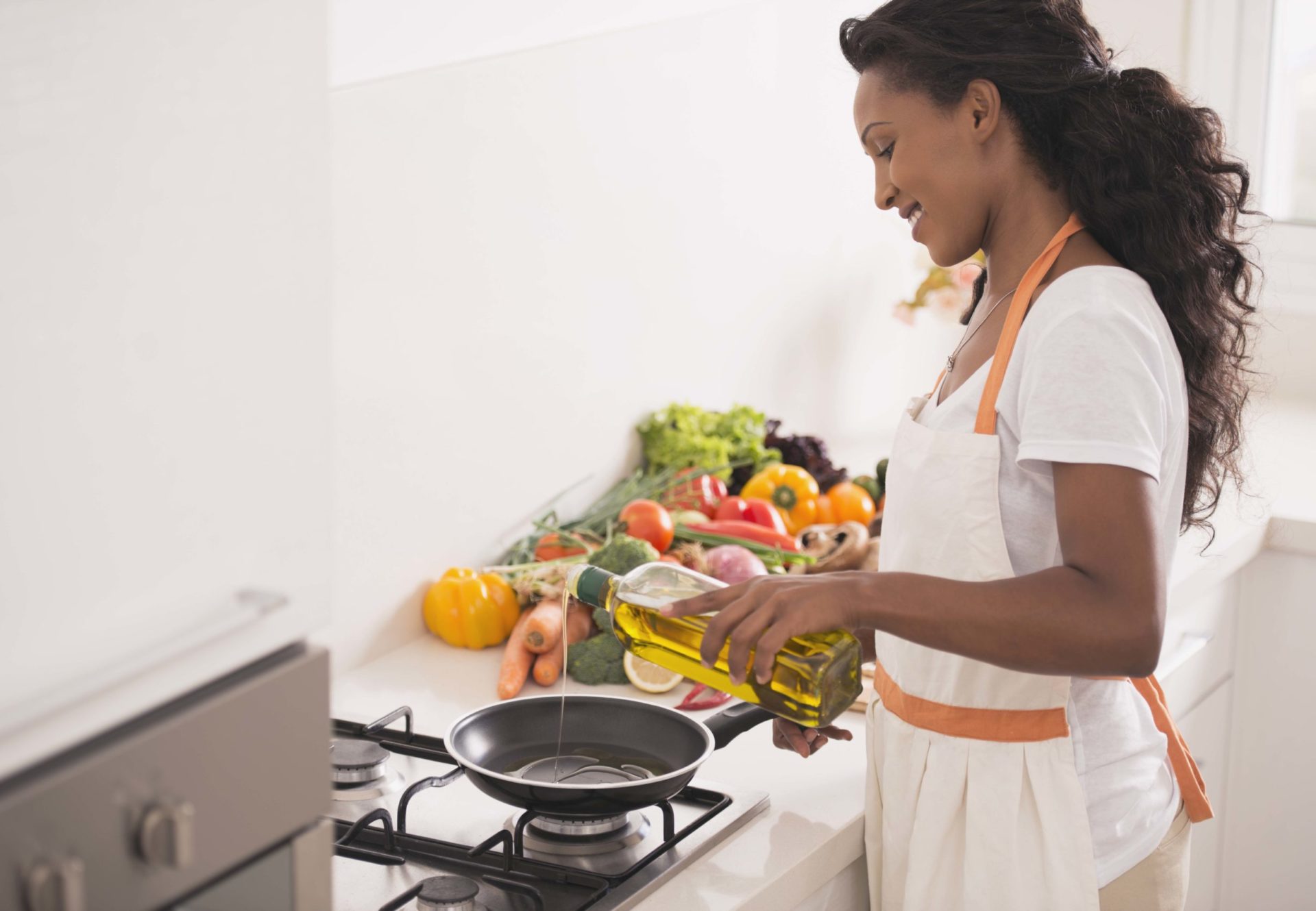 Woman dispensing edible oil into a pan to cook food