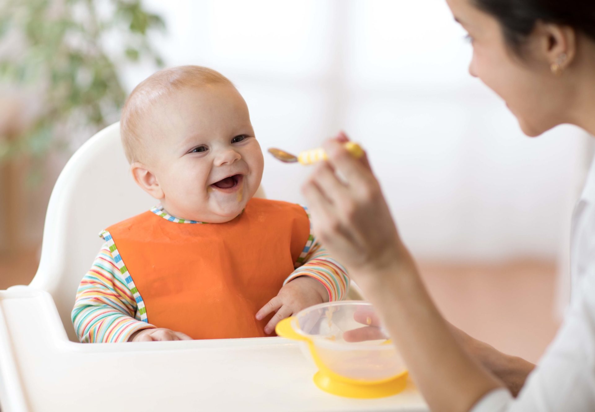 Mother feeding an infant in a highchair