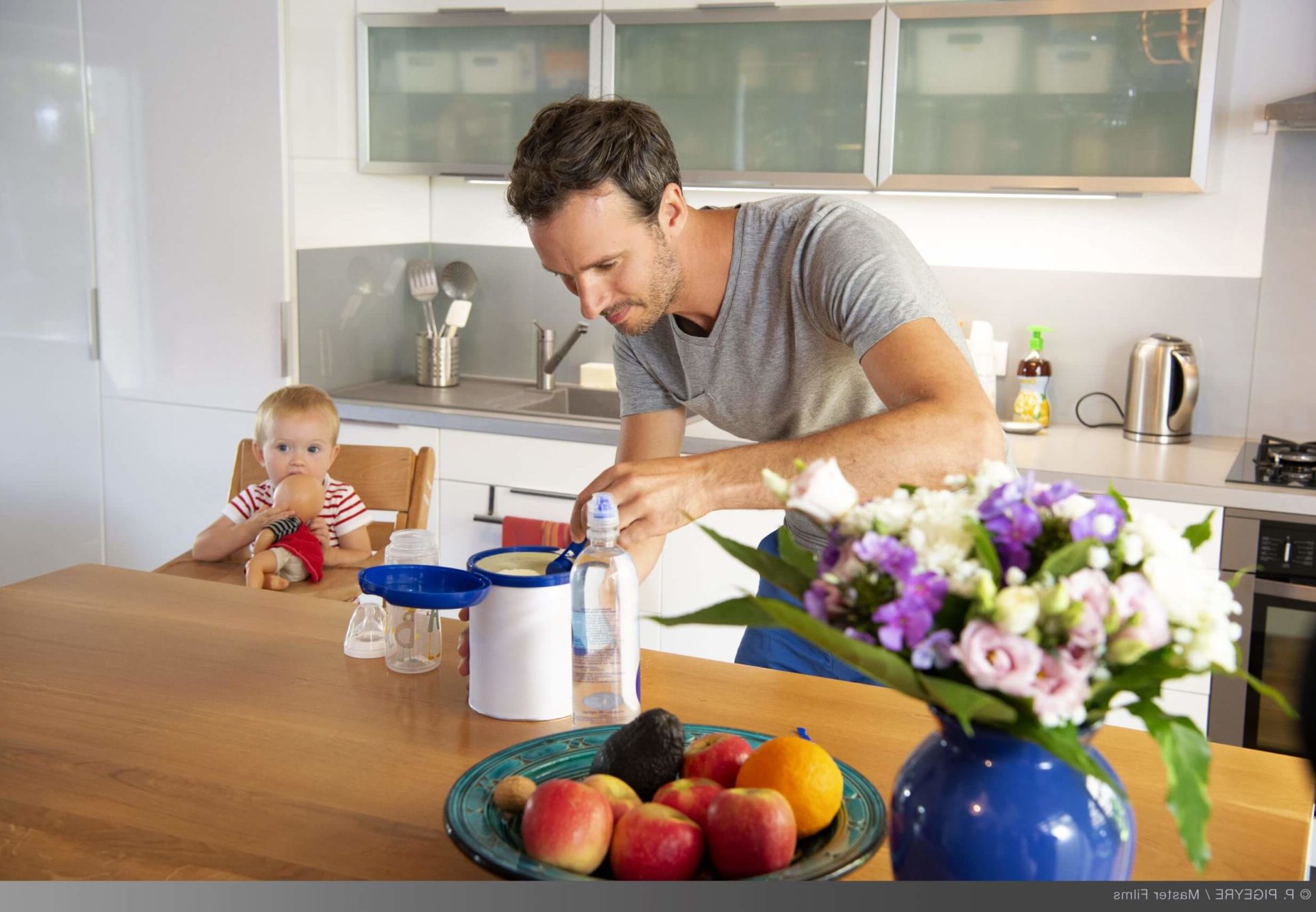 Father preparing infant son's formula in kitchen