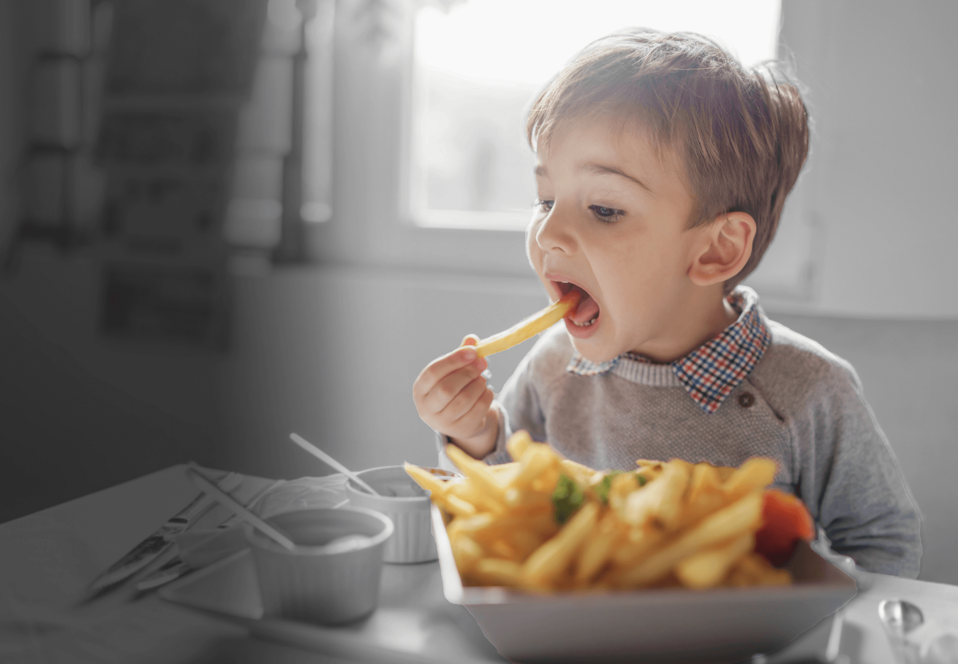 Little boy eating french frieswith sauces