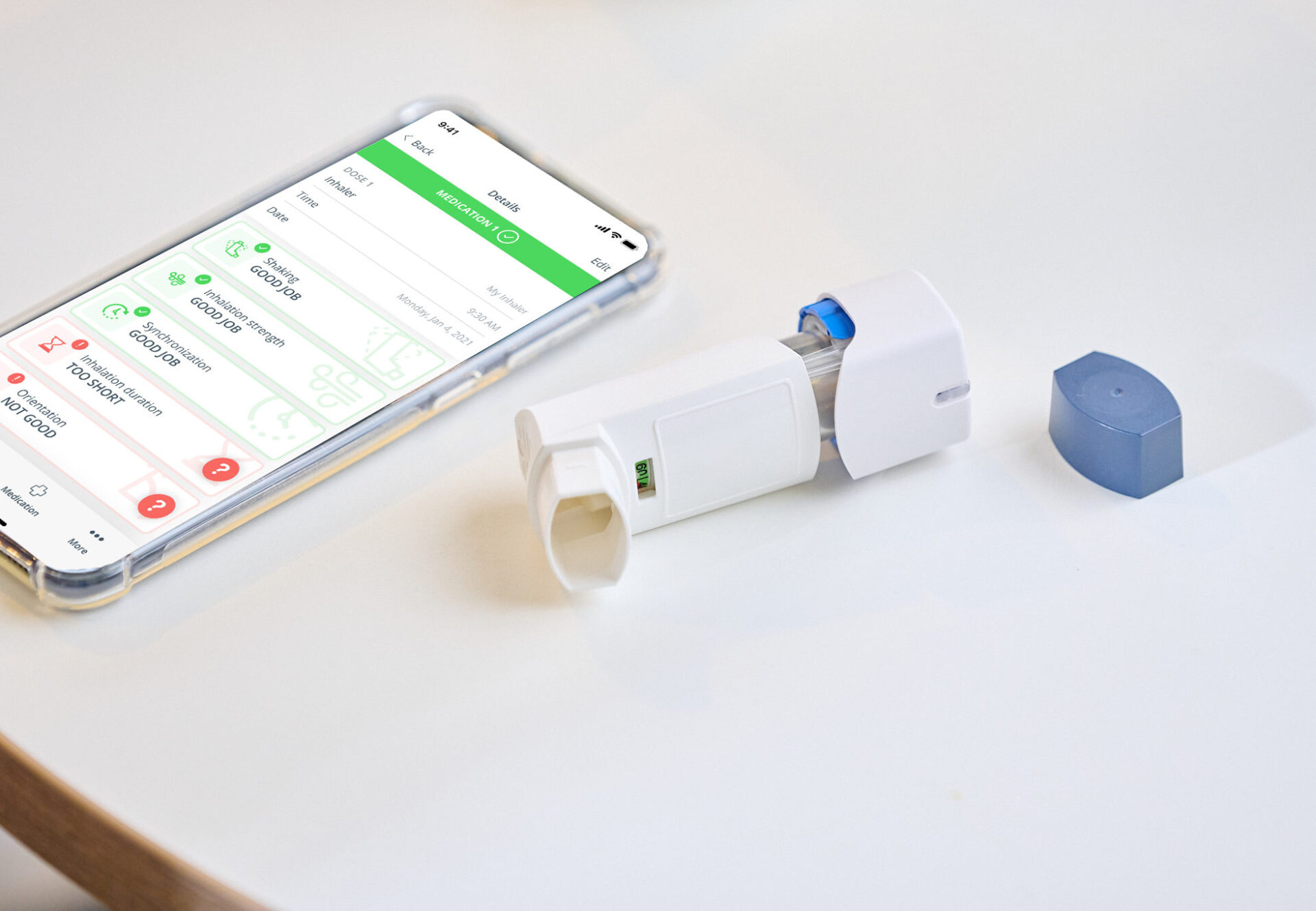 Aptar digital health connected inhaler device on a white table beside smartphone.