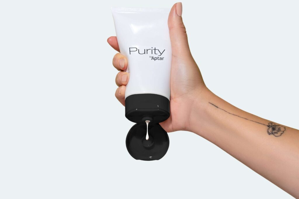 Purity tube top on gray background, squeezing lotion, sunscreen