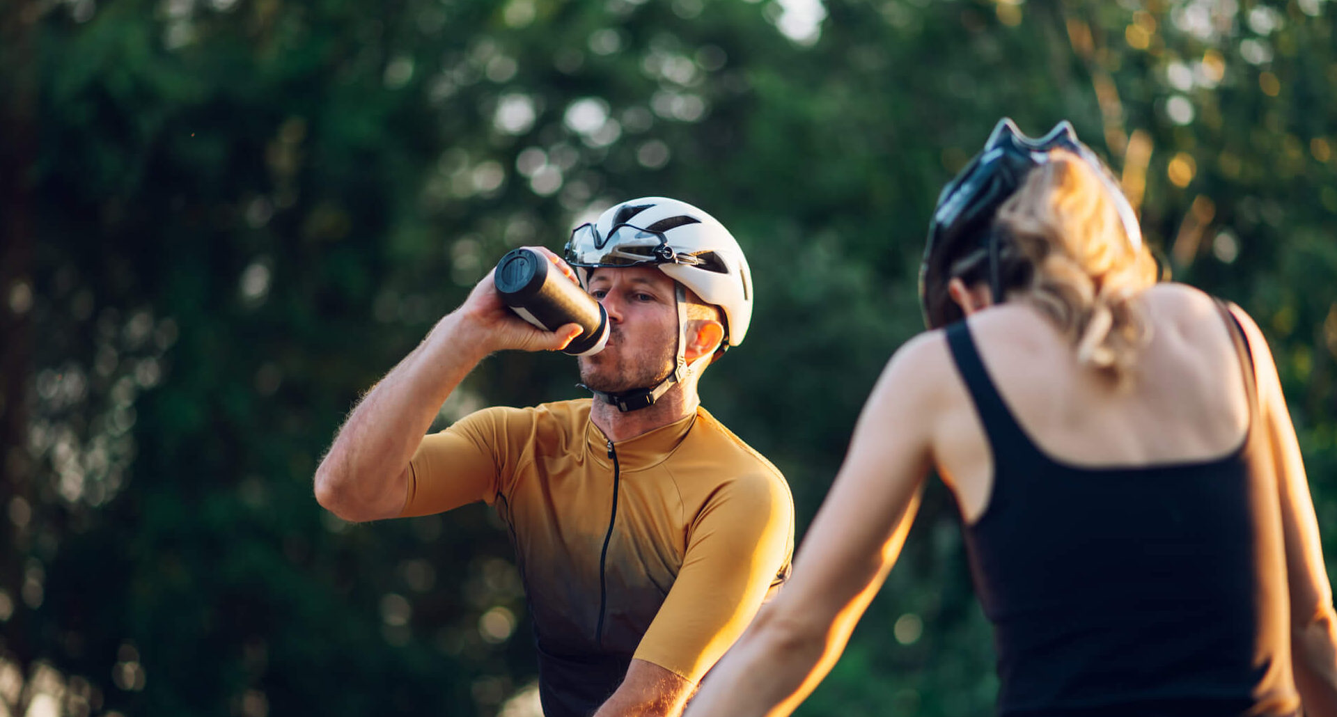 Couple riding bikes, stopping for water break